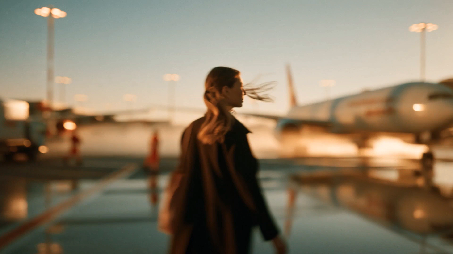 A traveller crossing an airport apron at dusk.